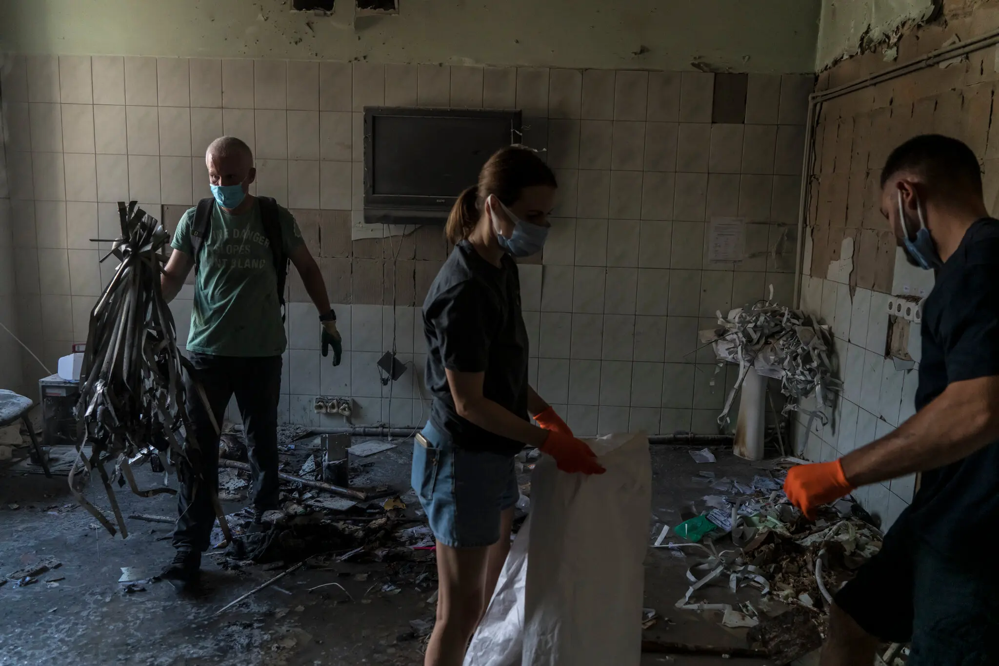 Волонтери прибирають уламки будівлі поруч з тією, яка постраждала від російського ракетного удару.